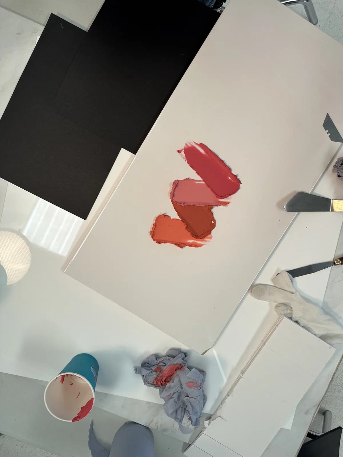 Three lipstick swatches on a studio surface, surrounded by lighting equipment and preparation materials